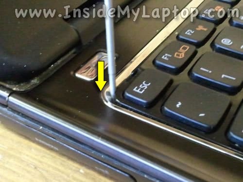 Insert screwdriver under keyboard