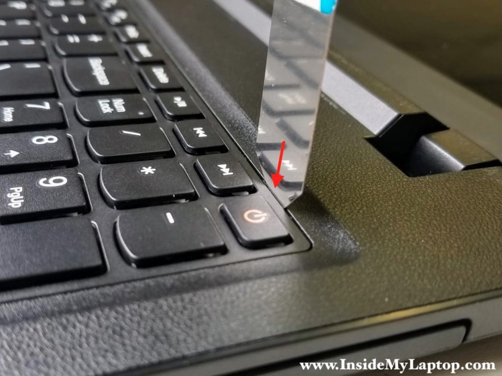 Insert case opening tool in the gap above keyboard