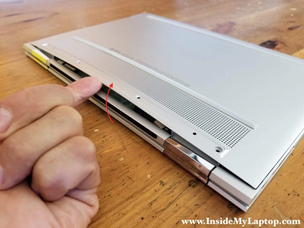 Start separating the bottom cover from the laptop on the back.