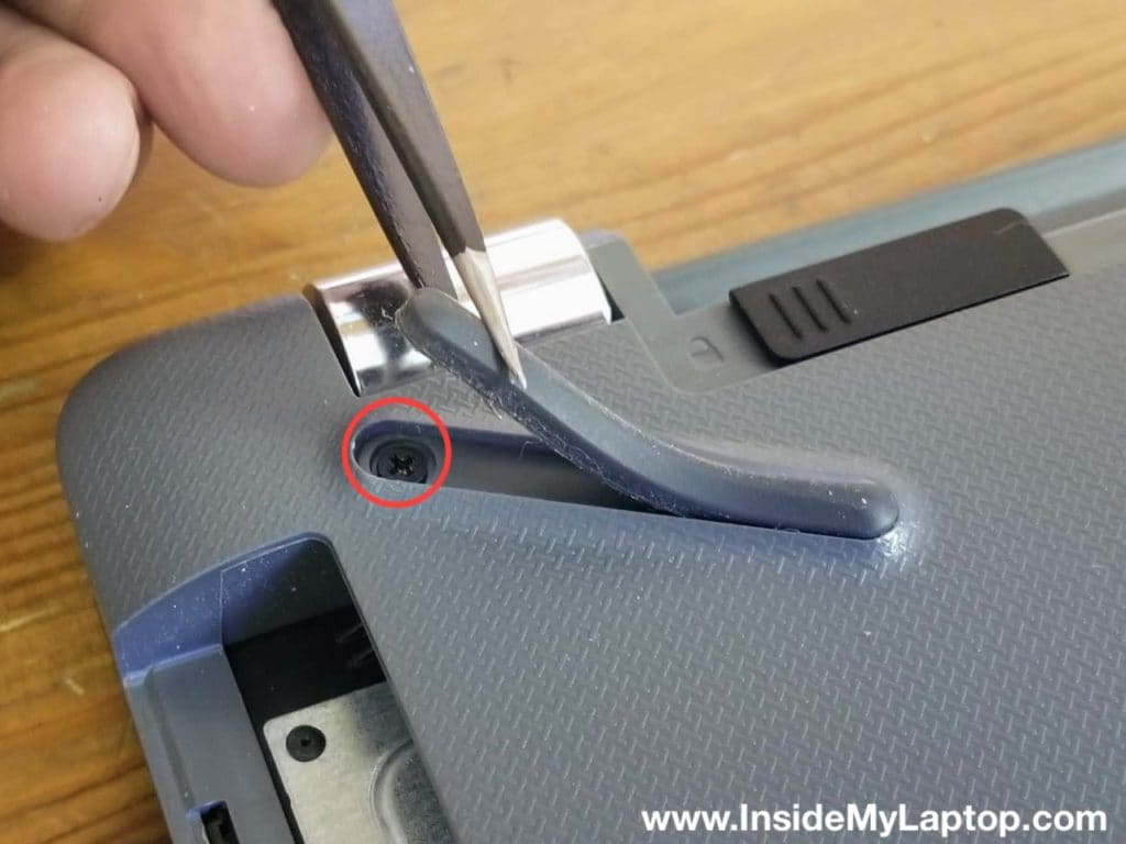 Hidden screw under the rubber foot on the bottom case.