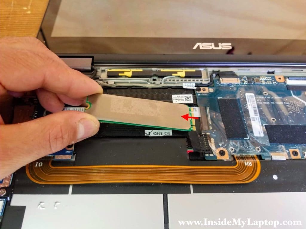 Remove one screw securing the solid state drive. Pull the SSD out of the slot and remove it.