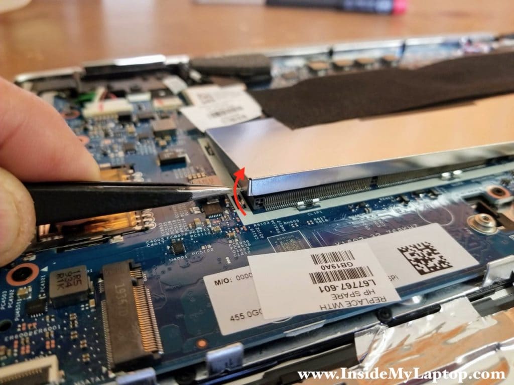 Carefully lift up one side of the RAM cover to separate it from the metal clamps on the motherboard.