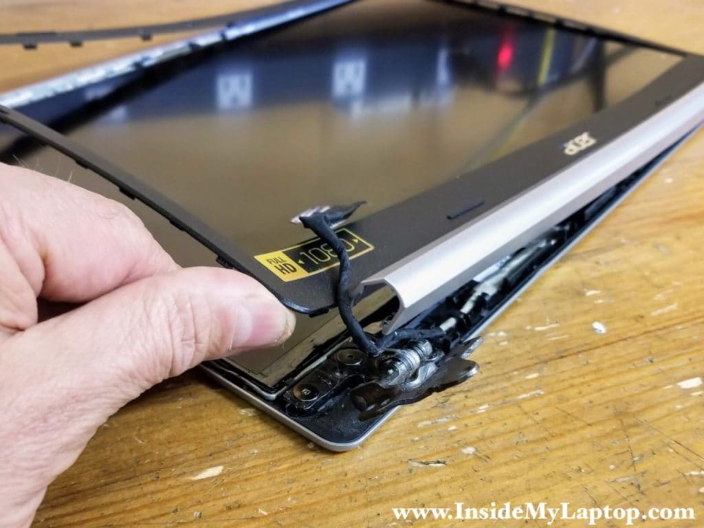 Lift up one side of the screen bezel and separate it from the hinge.