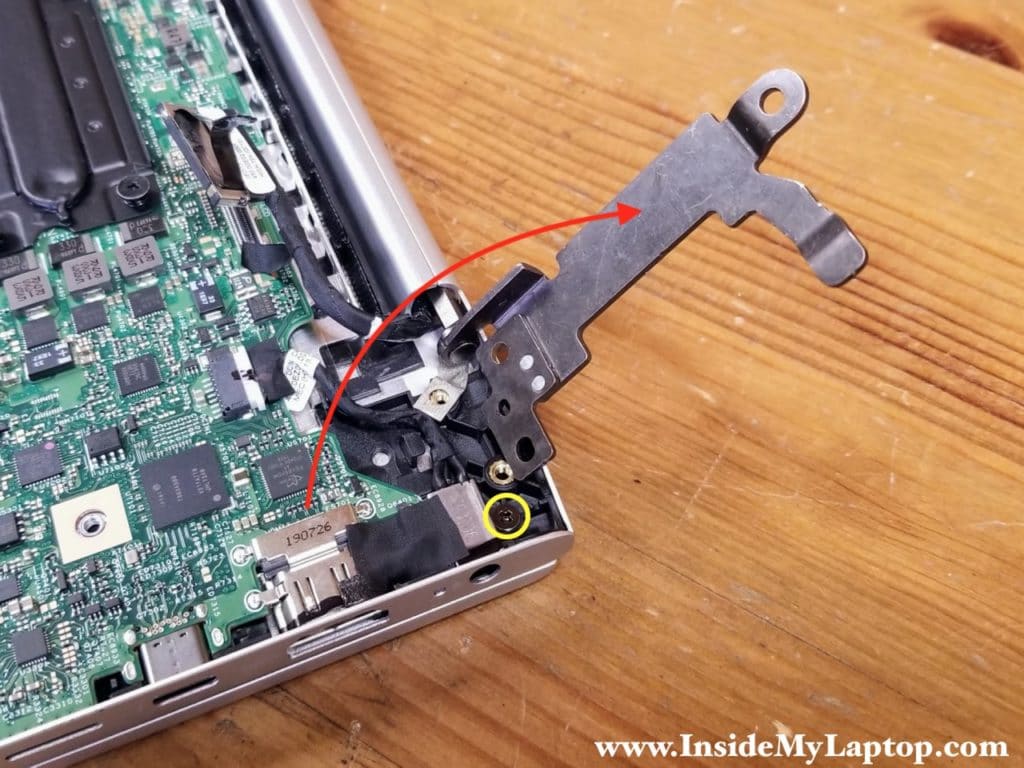 Lift up the left display hinge and remove one screw from the DC jack.