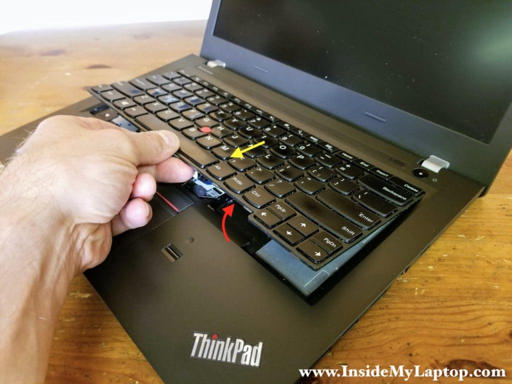 Separate the keyboard from the top case and pull towards the touchpad.