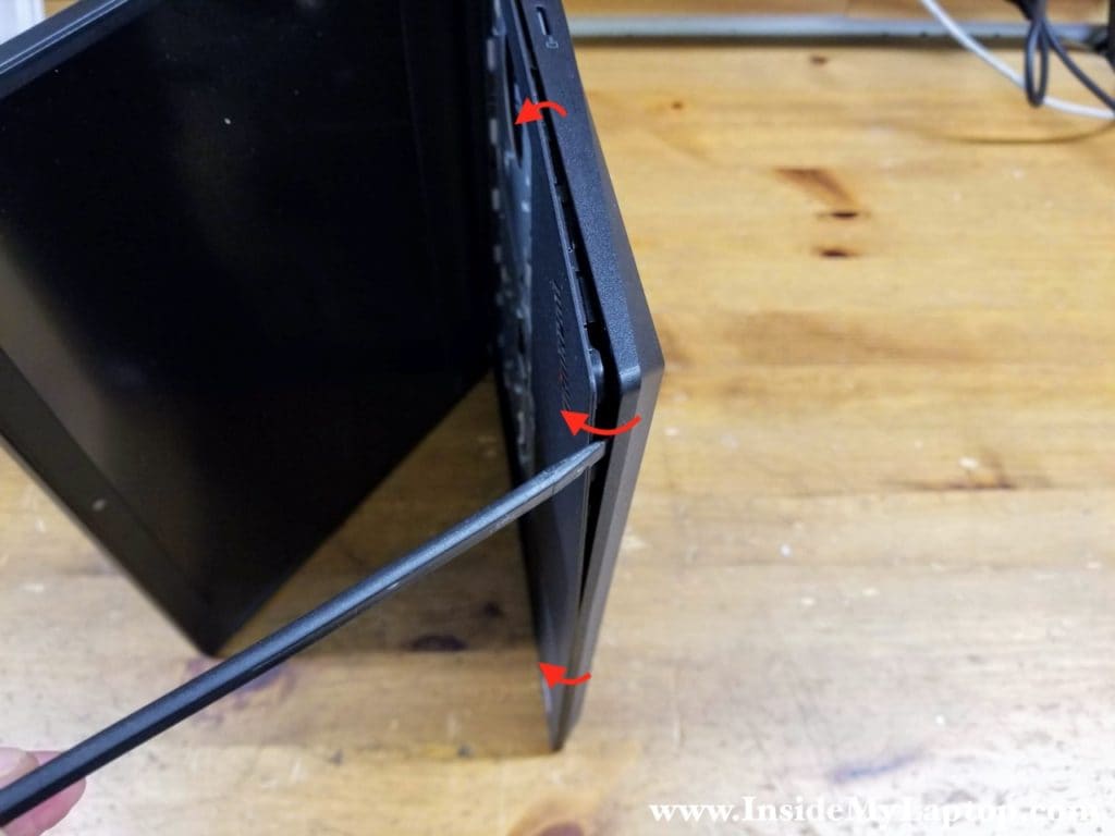 Place the laptop on its side and start separating the top case from the base cover.