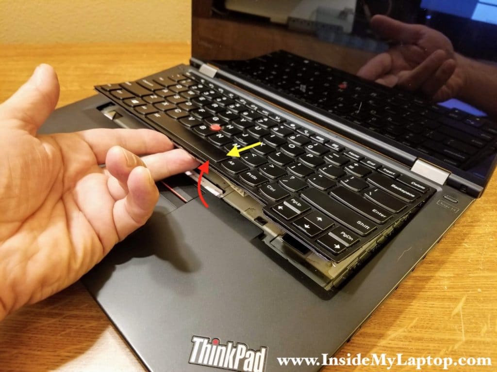 Lift up the lower side of the keyboard and pull it towards the touchpad.