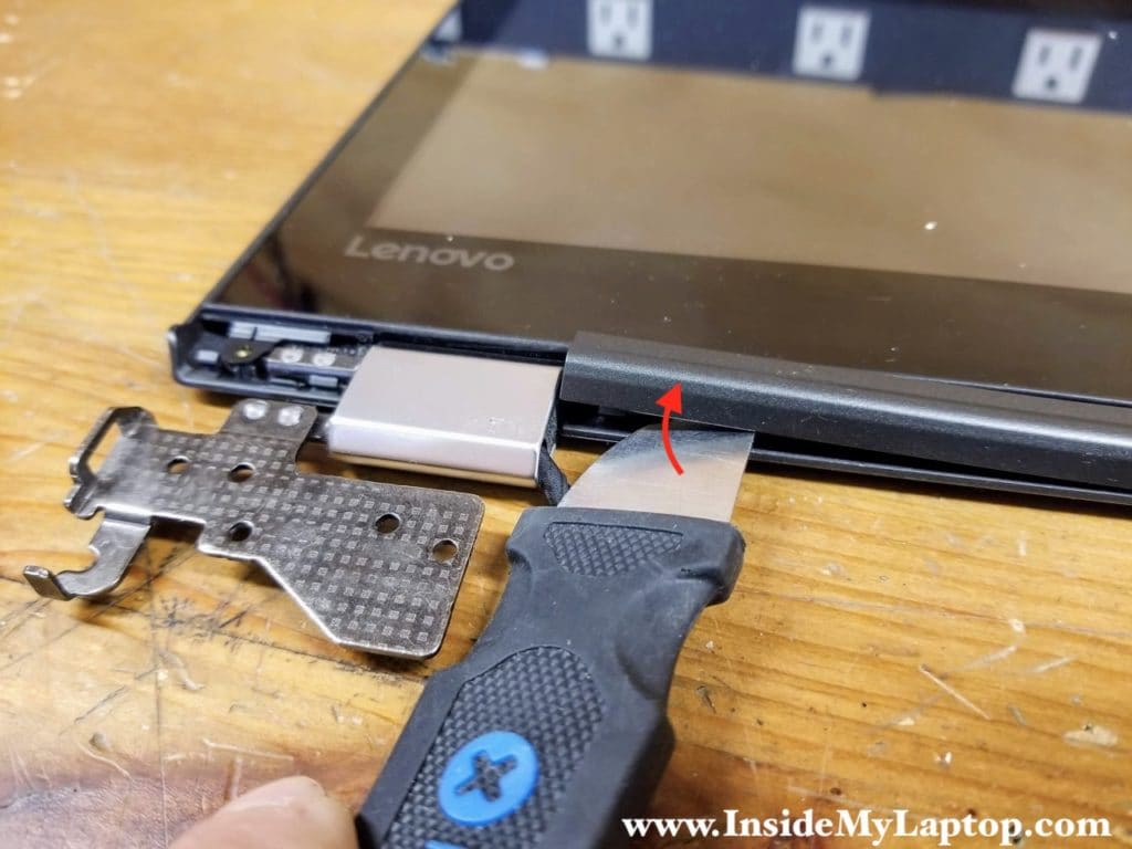 Start removing the cover located between the display hinges.