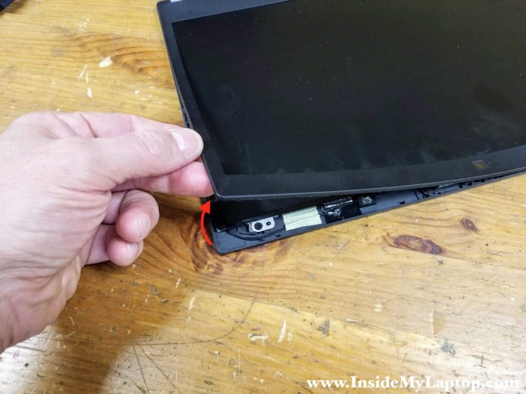 Carefully separate the screen bezel from the display and remove it.