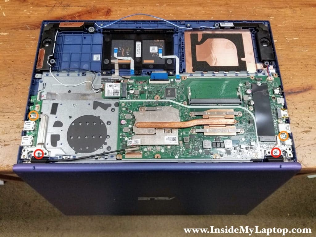 Turn the laptop upside down and remove four screws securing the display hinges.